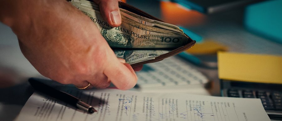 Cash being handed across a desk over a signed document