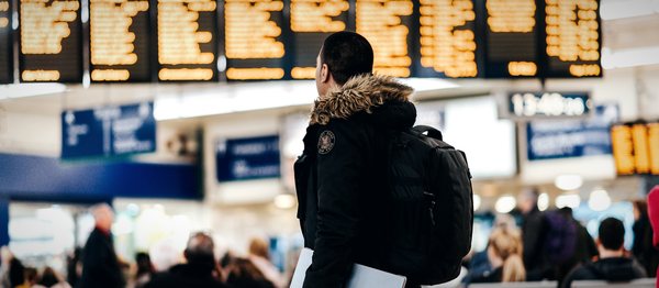 A traveller with a backpack reading an airport departure board
