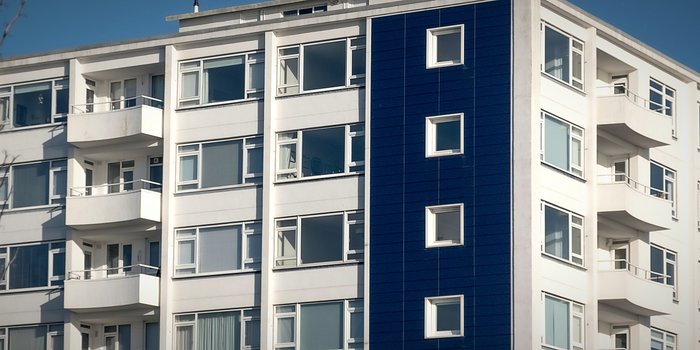 A modern residential apartment block with balconies against a clear sky