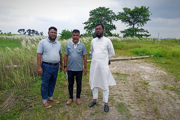 Three members of the team on the brick access road beside kash grass